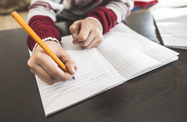 Close of child's hand writing in notebook