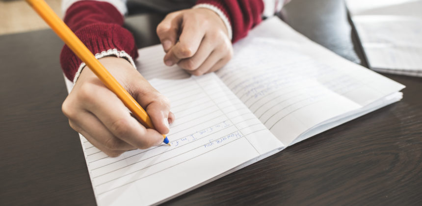 Close of child's hand writing in notebook