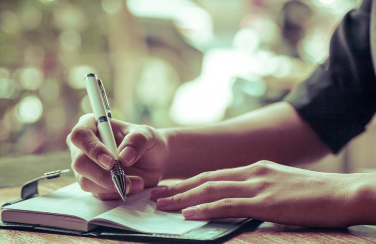 Teenage boy writing in his agenda