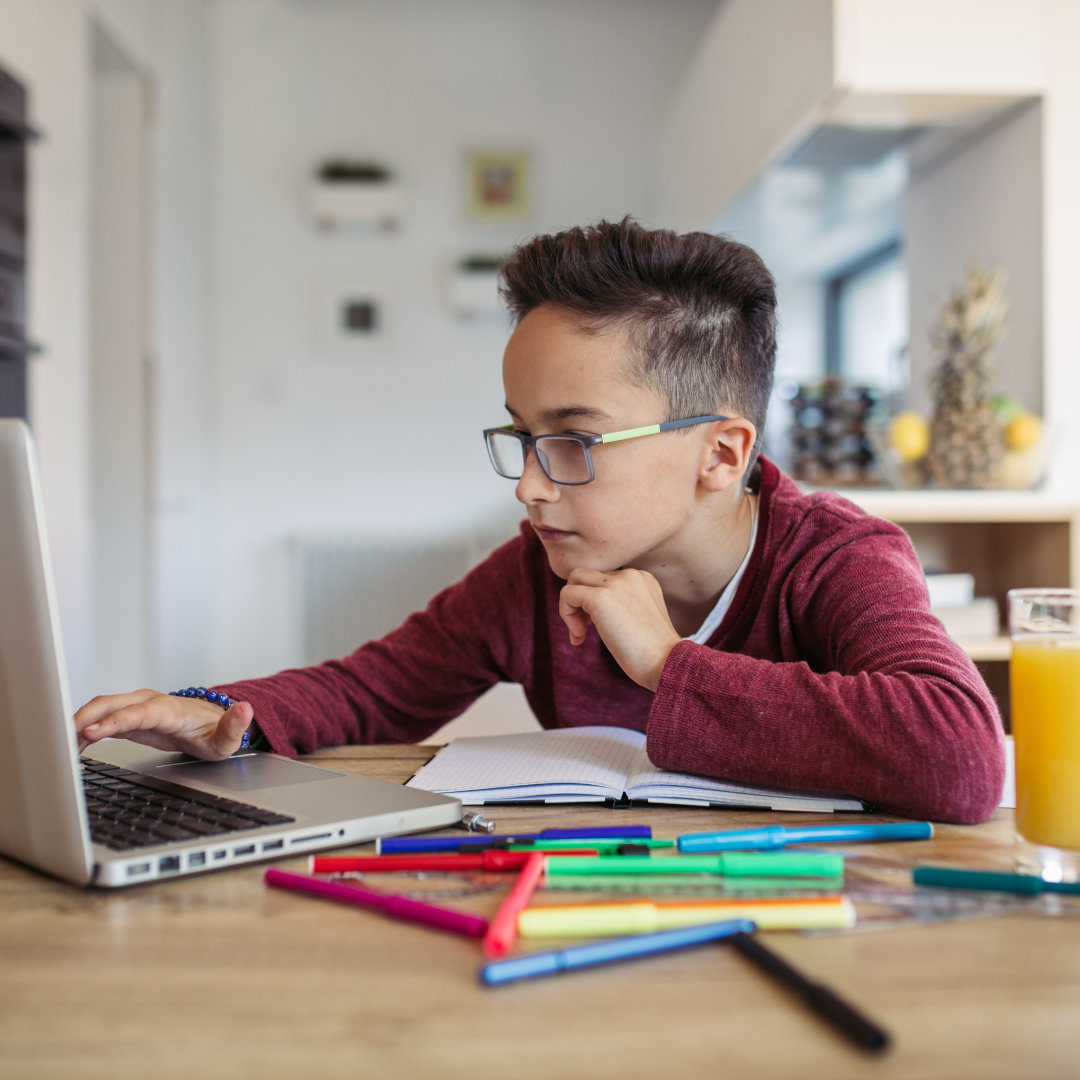 A young boy is studying at home on a laptop using our special virtula tutoring service.