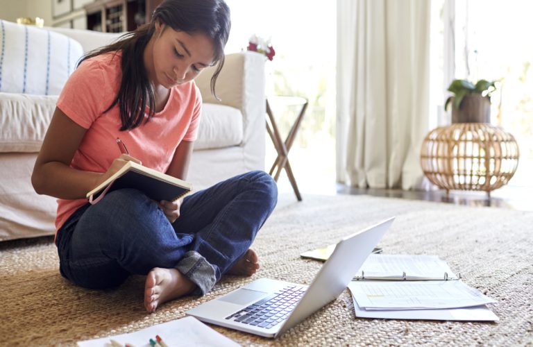 A young female student working on homework in her room.