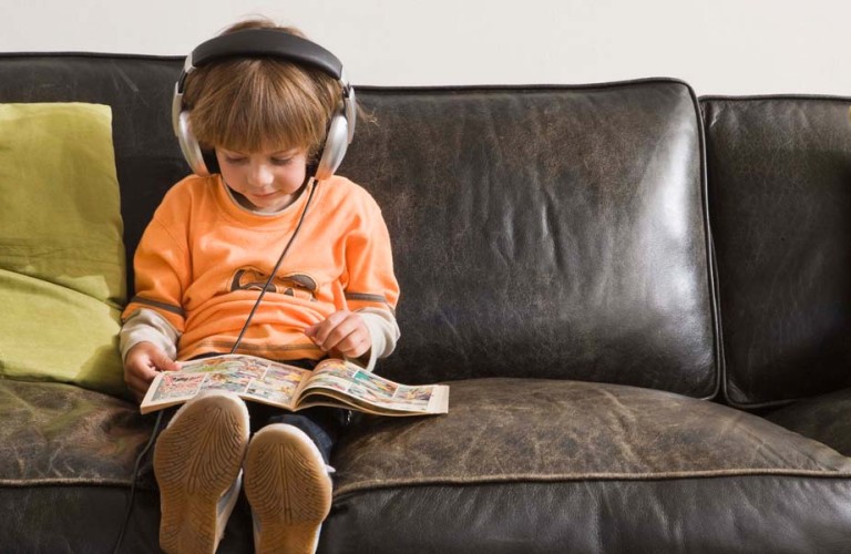 Child reading a comic book on a coach