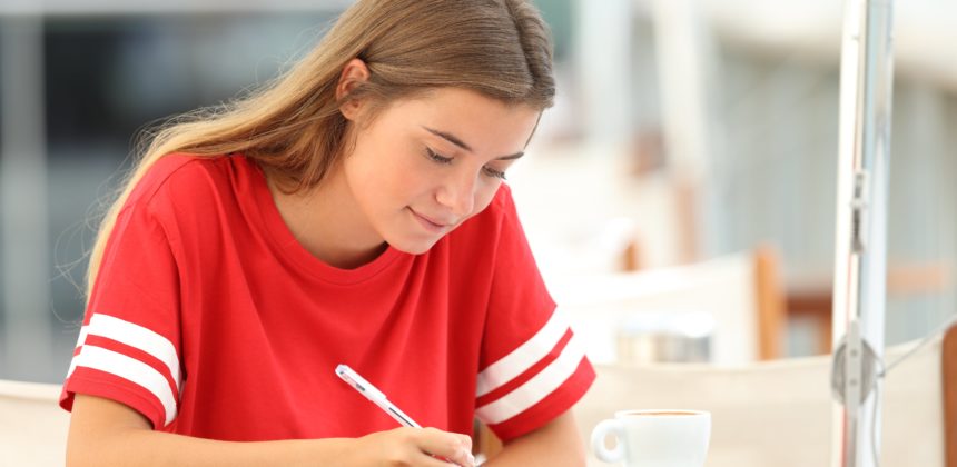 High school student writing in a notebook.